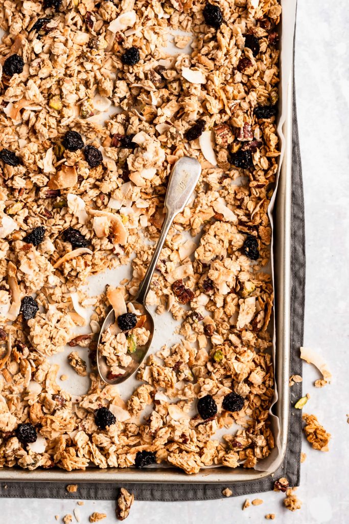 baking sheet with coconut tahini pistachio granola and a spoon